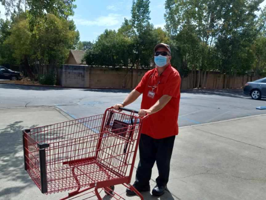 young man in a red shirt with a medical mask, collecting shopping carts